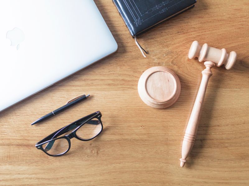 Vista dall'alto di laptop, occhiali, martello e penna su sfondo di legno su scrivania di legno